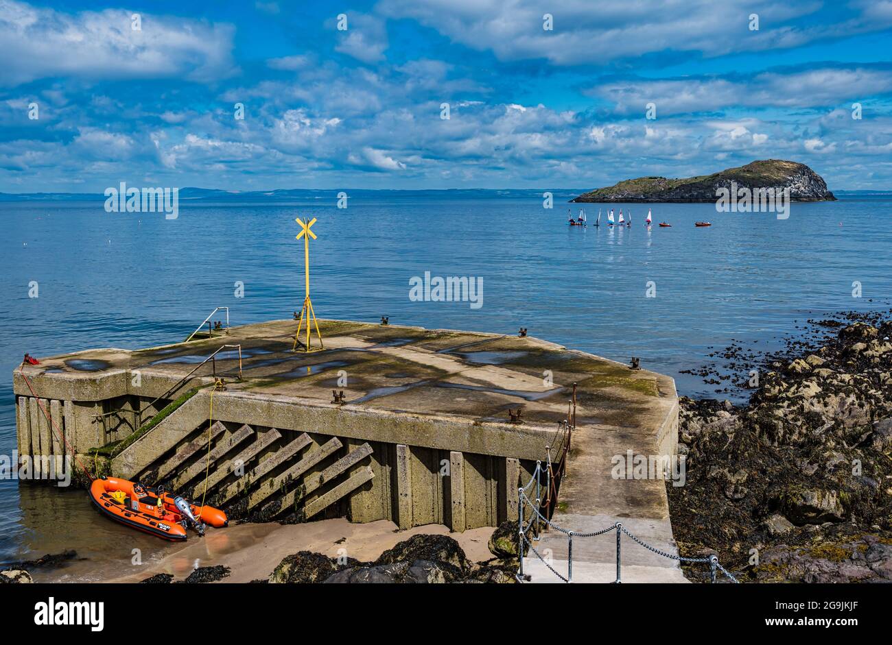 Sailing dinghies by Craigleith Island in Firth of Forth with old pier on sunny Summer day, North Berwick, Scotland, UK Stock Photo