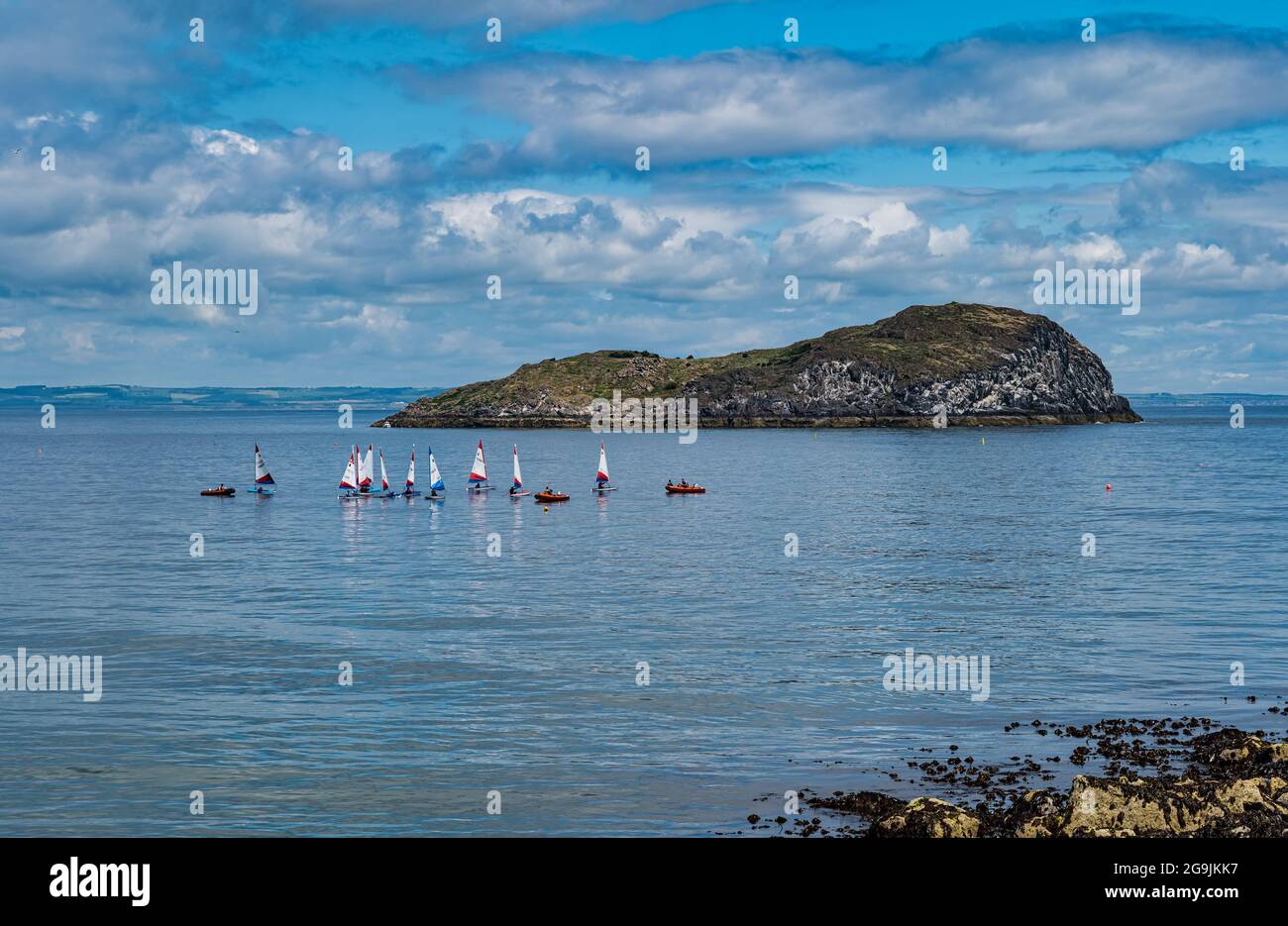 Sailing dinghies by Craigleith Island in Firth of Forth on a sunny Summer day with blue sky and clouds, Scotland, UK Stock Photo