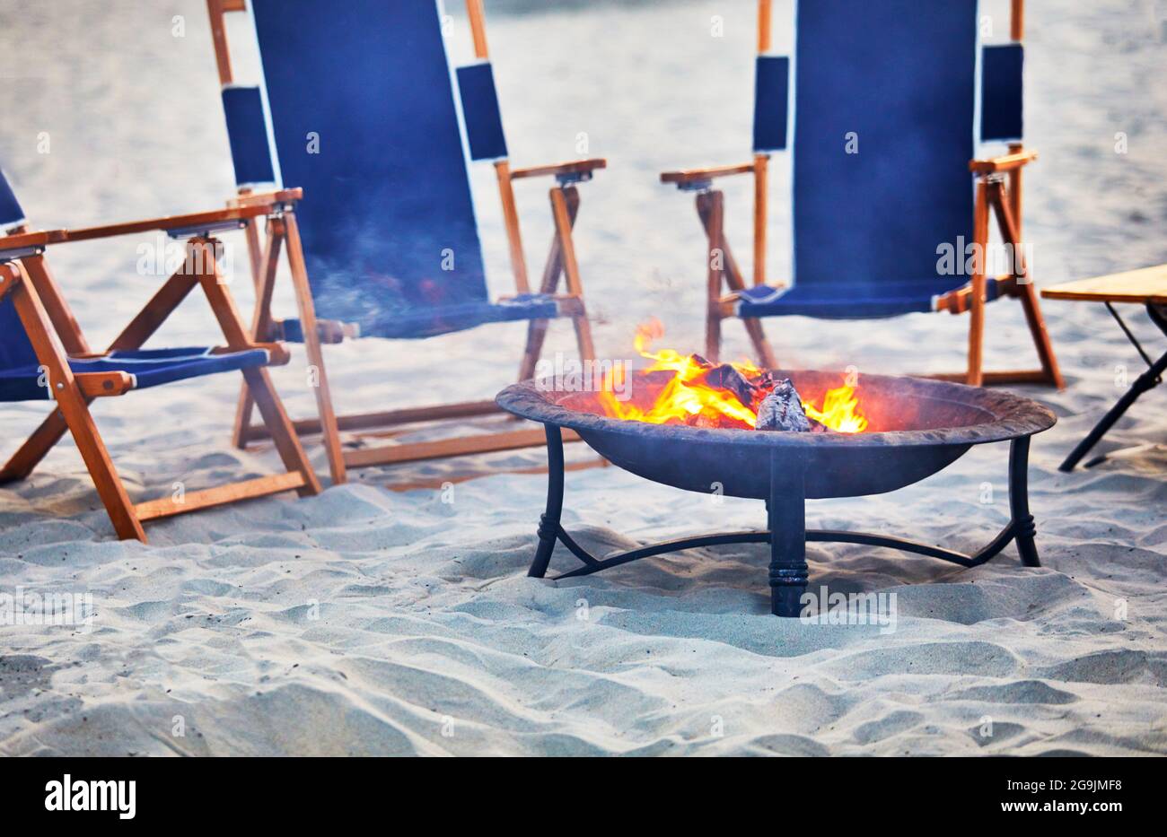 Fire pit on the beach with empty lounge chairs Stock Photo Alamy