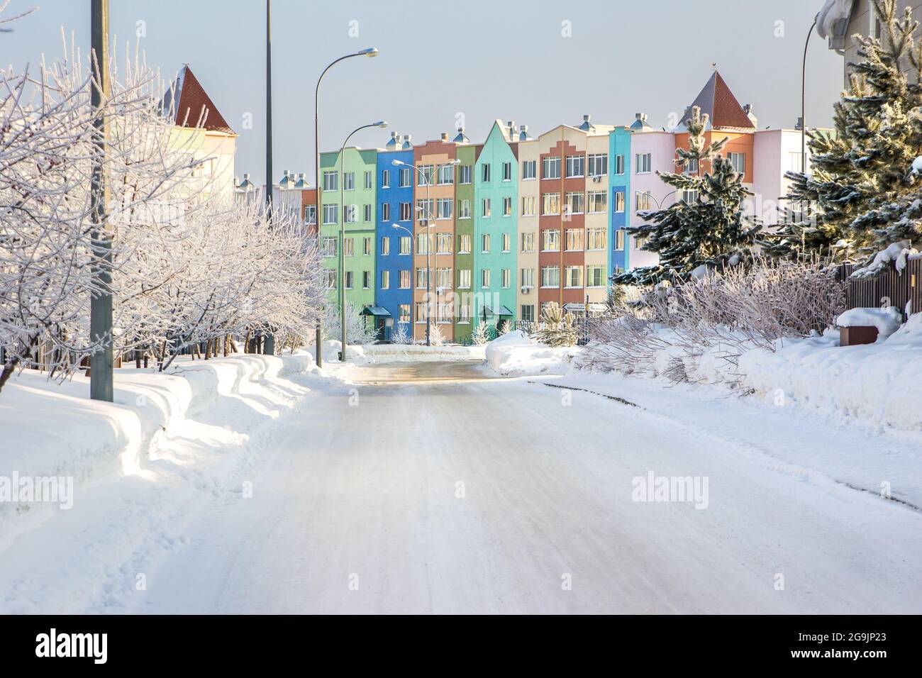 snowy street leading to a multi-colored multi-storey building Stock Photo