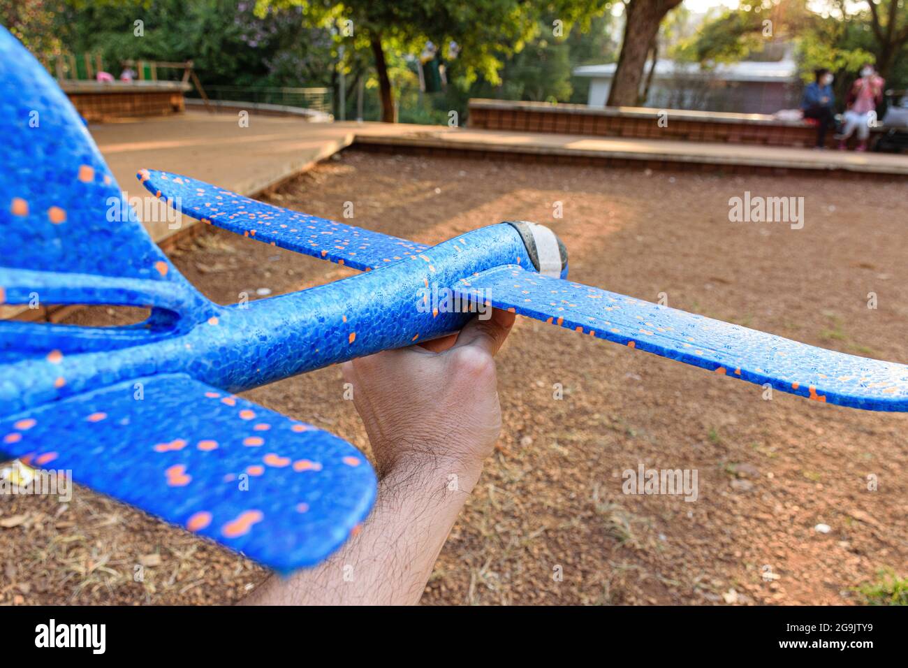 Closeup of a blue styrofoam plane with orange spots being held by adult hand. Stock Photo