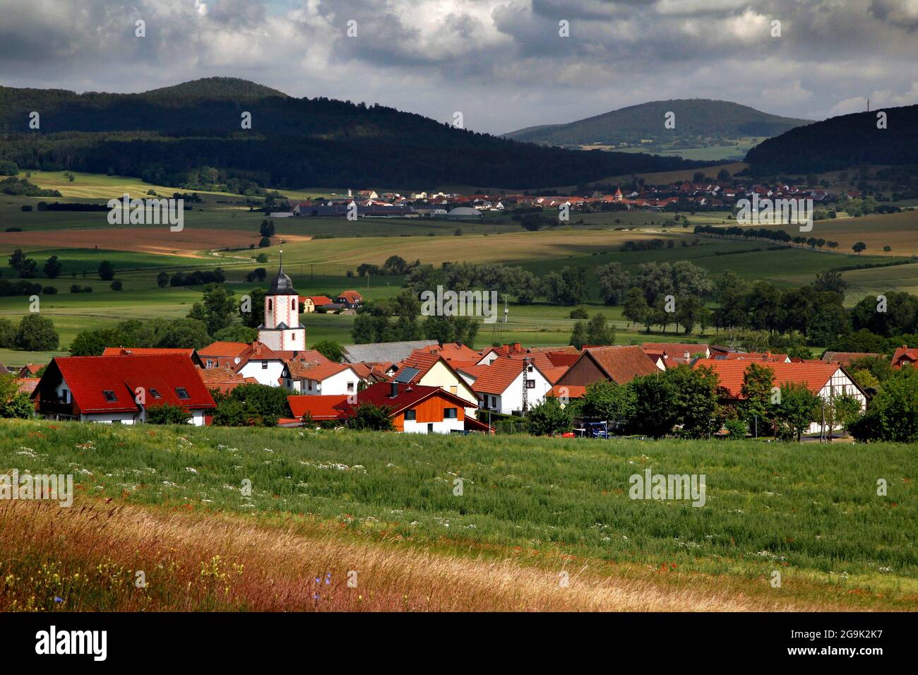 View of village and Rhoen, hiking trail through meadows and fields, Lochplattenweg, Gruenes Band, border trail, former German-German border Stock Photo