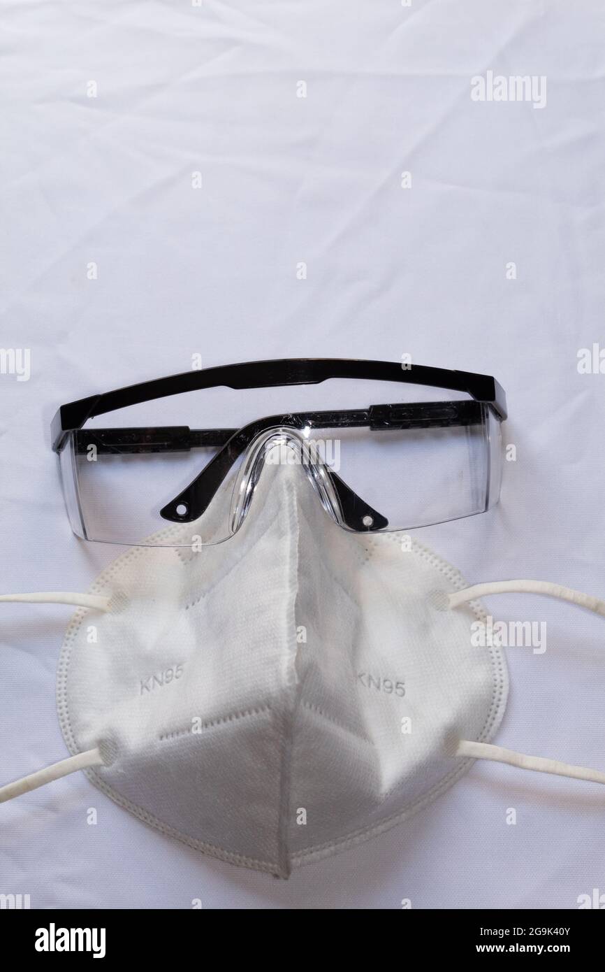 kn95 face mask and protective glasses on a wrinkled white background