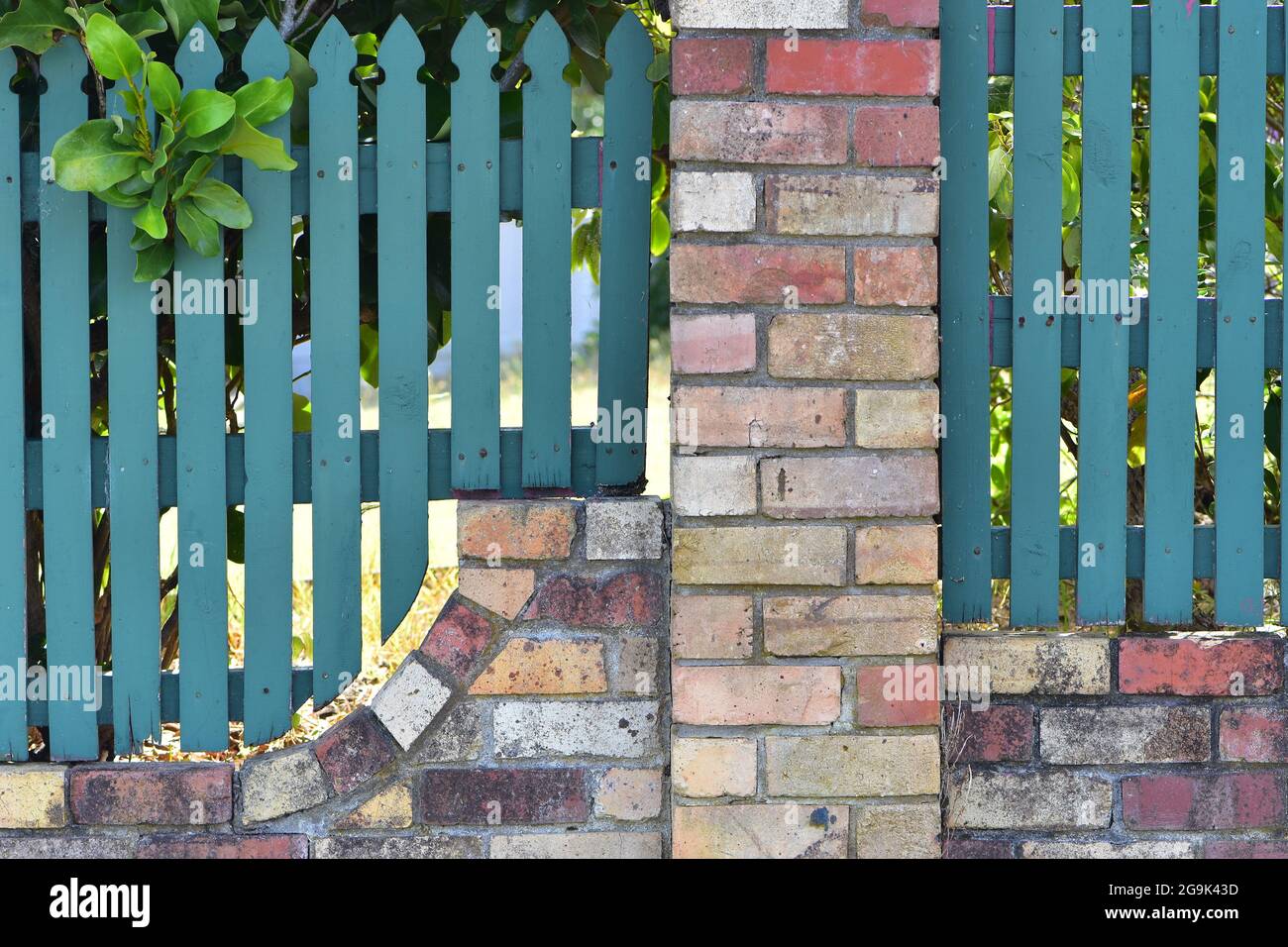 Picket yard fence with brick and mortar base and pillars. Stock Photo