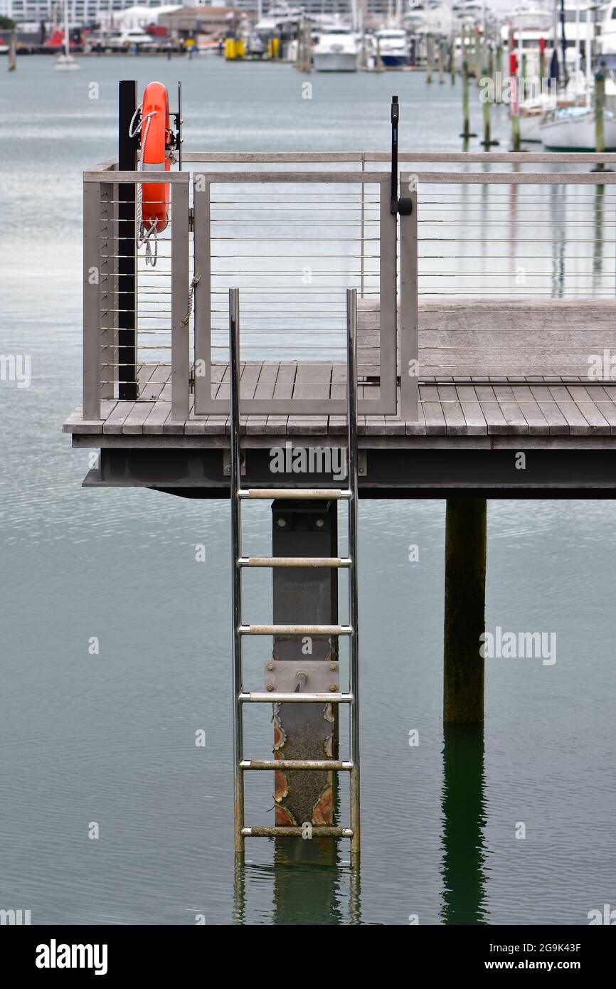 Steel marina jetty with timber floor and stainless steel ladder into water. Stock Photo