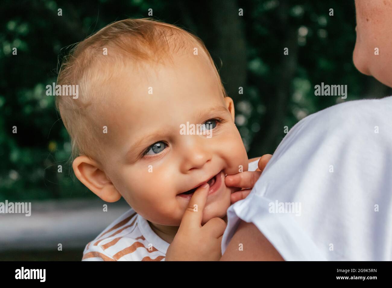 Little boy looks over his mother's shoulder. Stock Photo