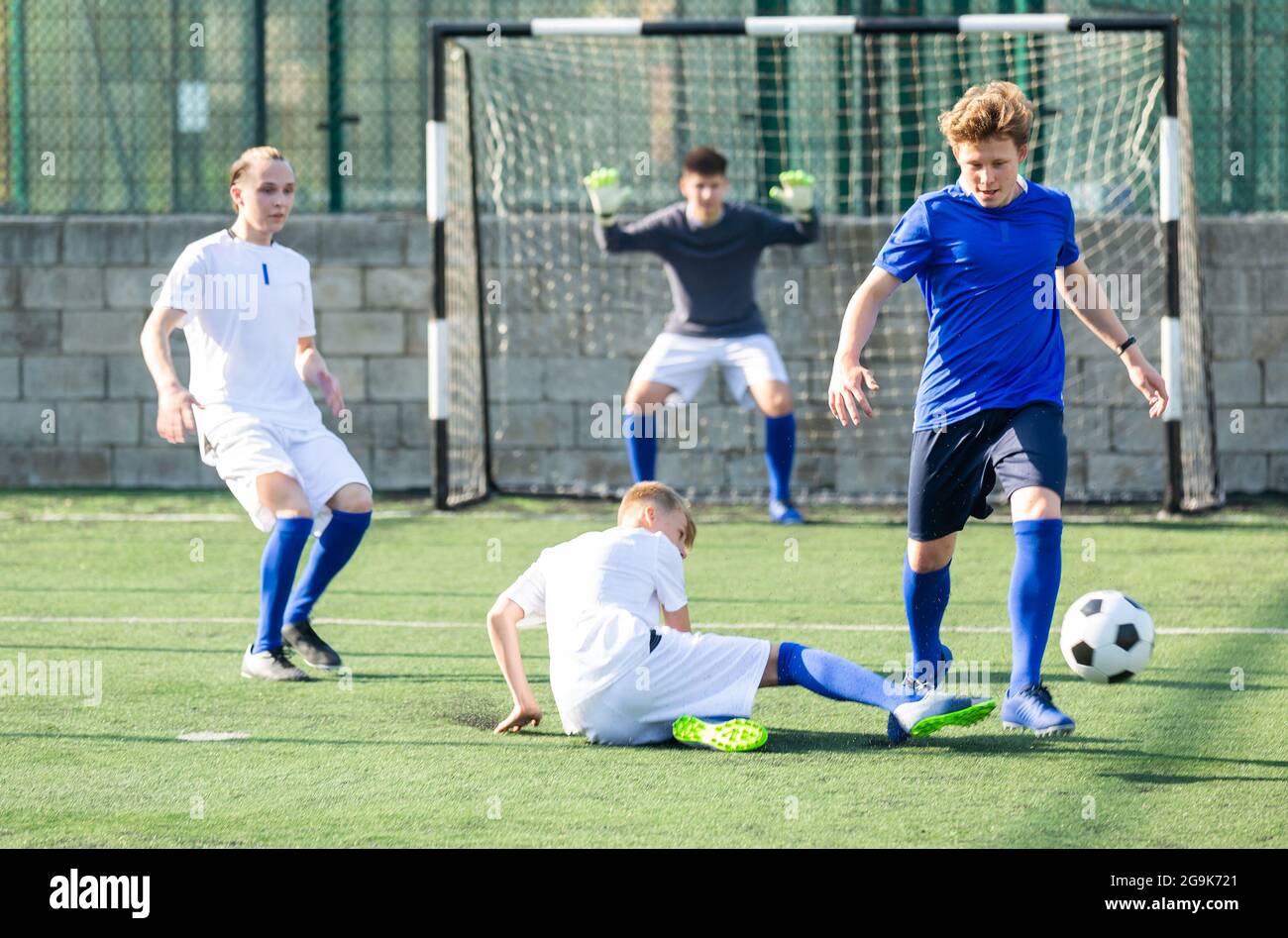 Game of football match between two teams of teenagers in white and blue shirts Stock Photo