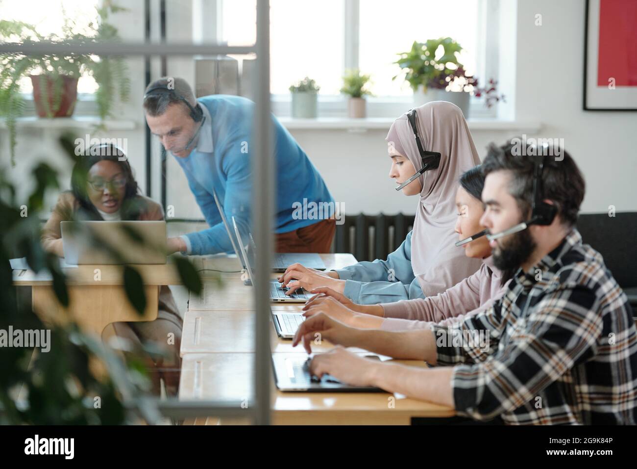 Young operators consulting clients online against two co-workers ...
