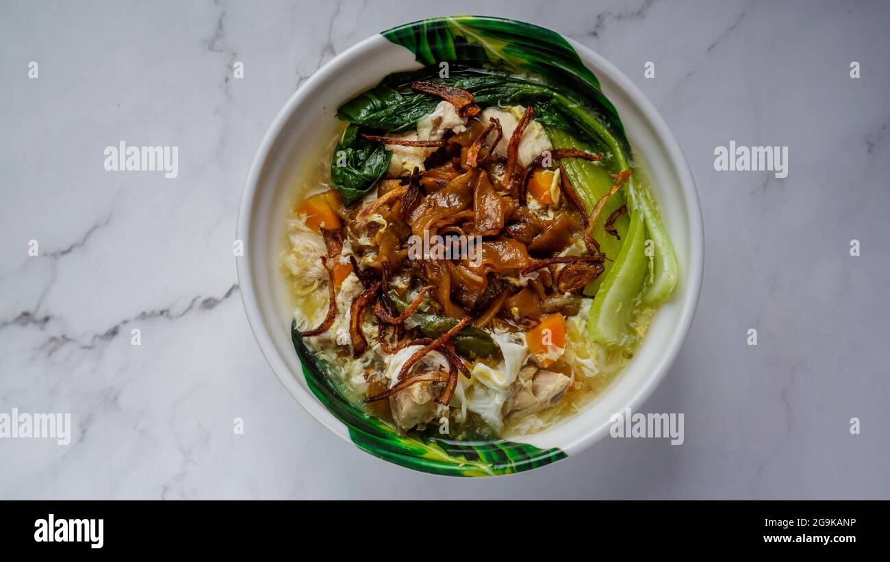 Flat Noodles cooked in Egg Gravy (Wan Tan Hor) with chicken bits and fish balls. Garnished with fried onions. A chinese cuisine served in Southeast As Stock Photo