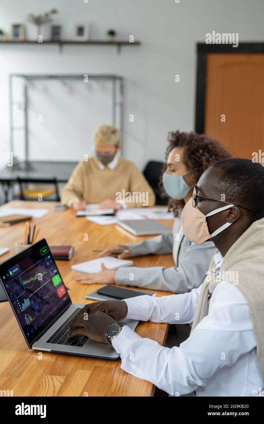 Row of young intercultural co-workers analyzing data and planning work Stock Photo