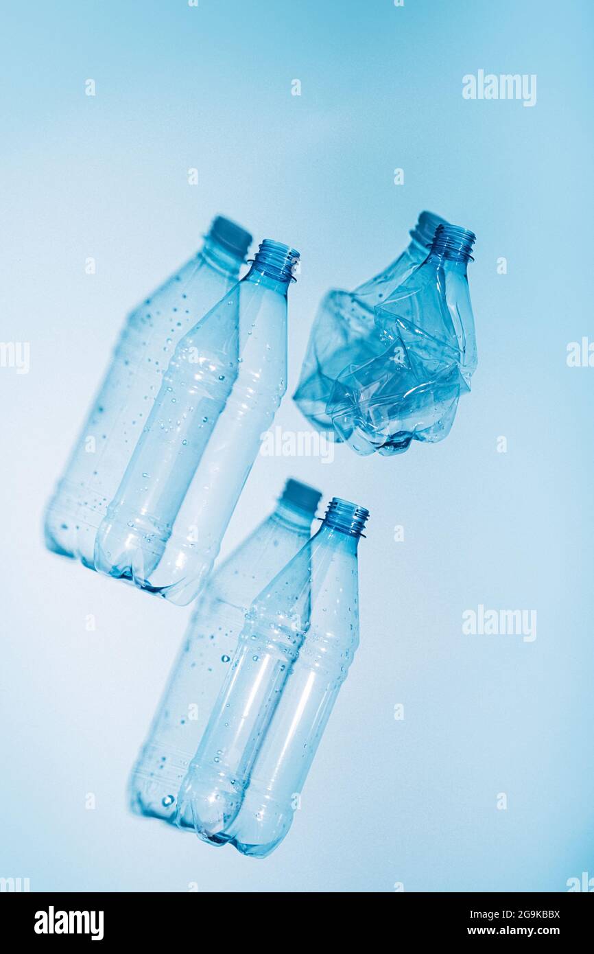 Plastic bottles with water and empty used on blue background. Recycling