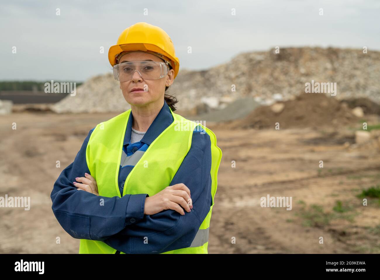 Serious female construction worker crossing arms by chest against ...