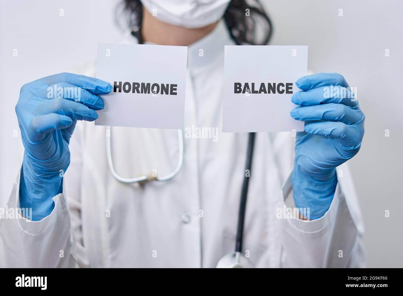 A female doctor holding two white cards with Hormone balance words. Hormone balance concept Stock Photo
