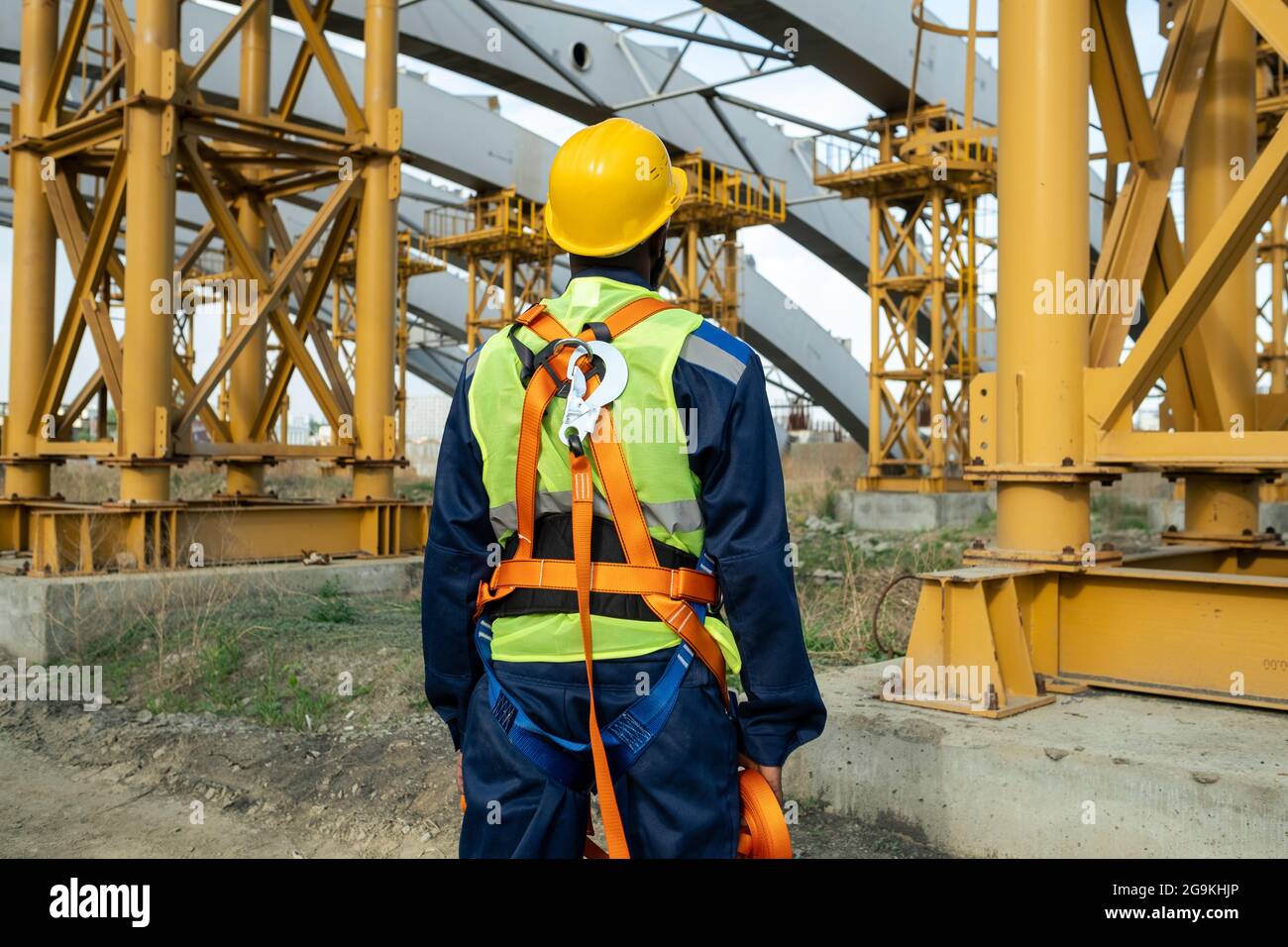 Rear view of construction worker in equipment and in work helmet working on construction site Stock Photo