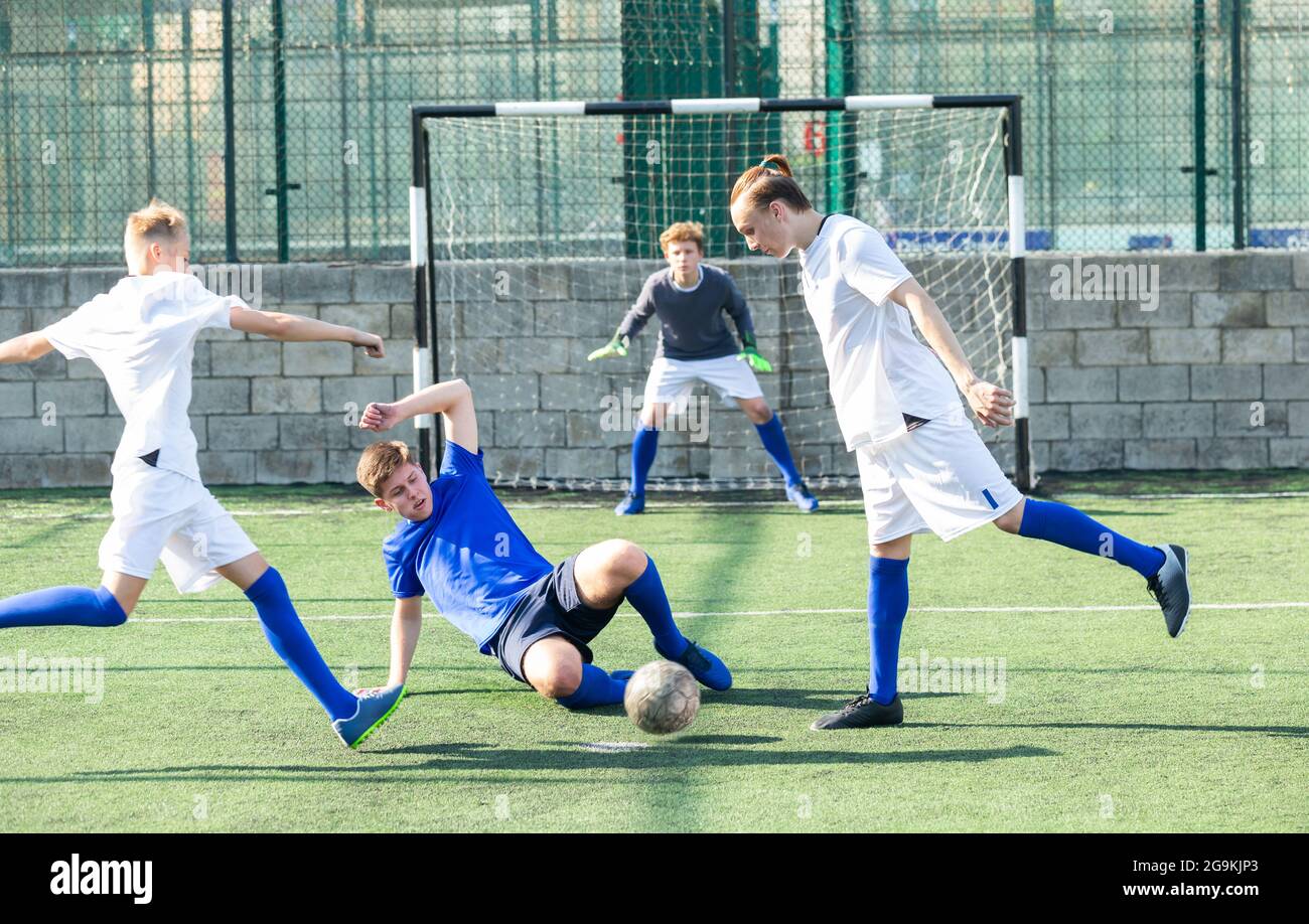Game of football match between two teams of teenagers in white and blue shirts Stock Photo