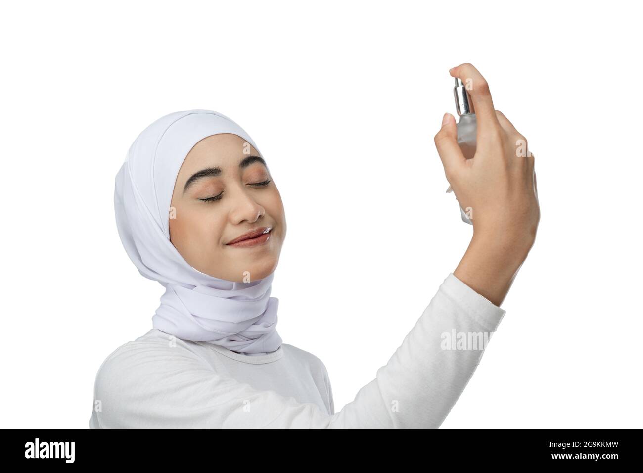 Excited asian hijab woman wearing white dress squirts a bottle of facial  care serum Stock Photo - Alamy