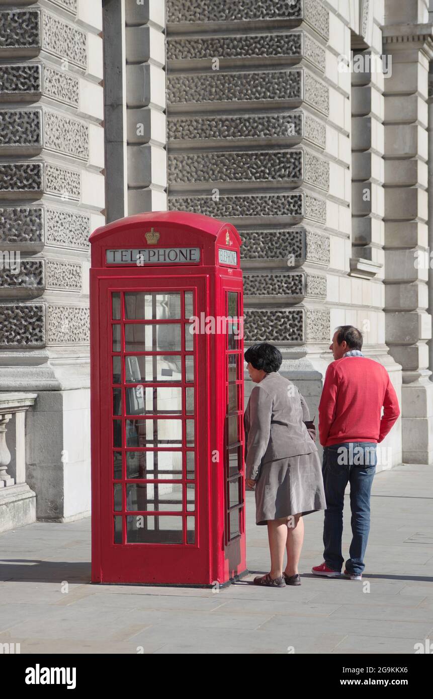 London, England - May 27, 2013: a femal tourist is looking into a red telephone box in London Westminster City. The red telephone boxes were introduce Stock Photo