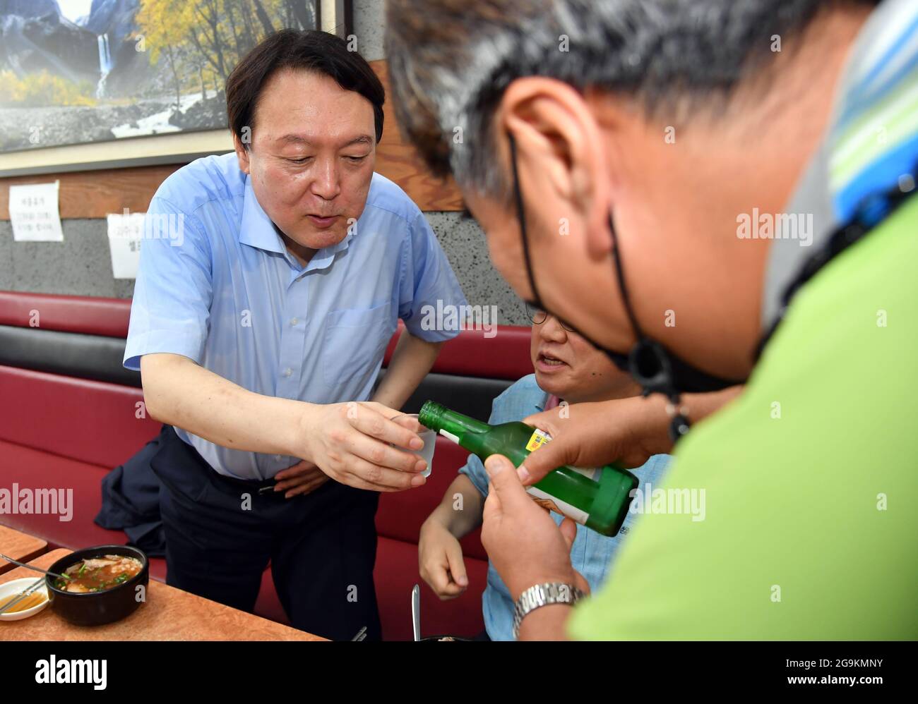 27th July, 2021. 27th July, 2021. Presidential hopeful at restaurant Former Prosecutor General Yoon Seok-youl (L), a presidential hopeful of the opposition bloc, receives a glass of soju, a distilled beverage made of ethanol and water, from a man at a pork soup restaurant in the southeastern port city of Busan on July 27, 2021. (Pool photo) Credit: Yonhap/Newcom/Alamy Live News Credit: Yonhap/Newcom/Alamy Live News Stock Photo