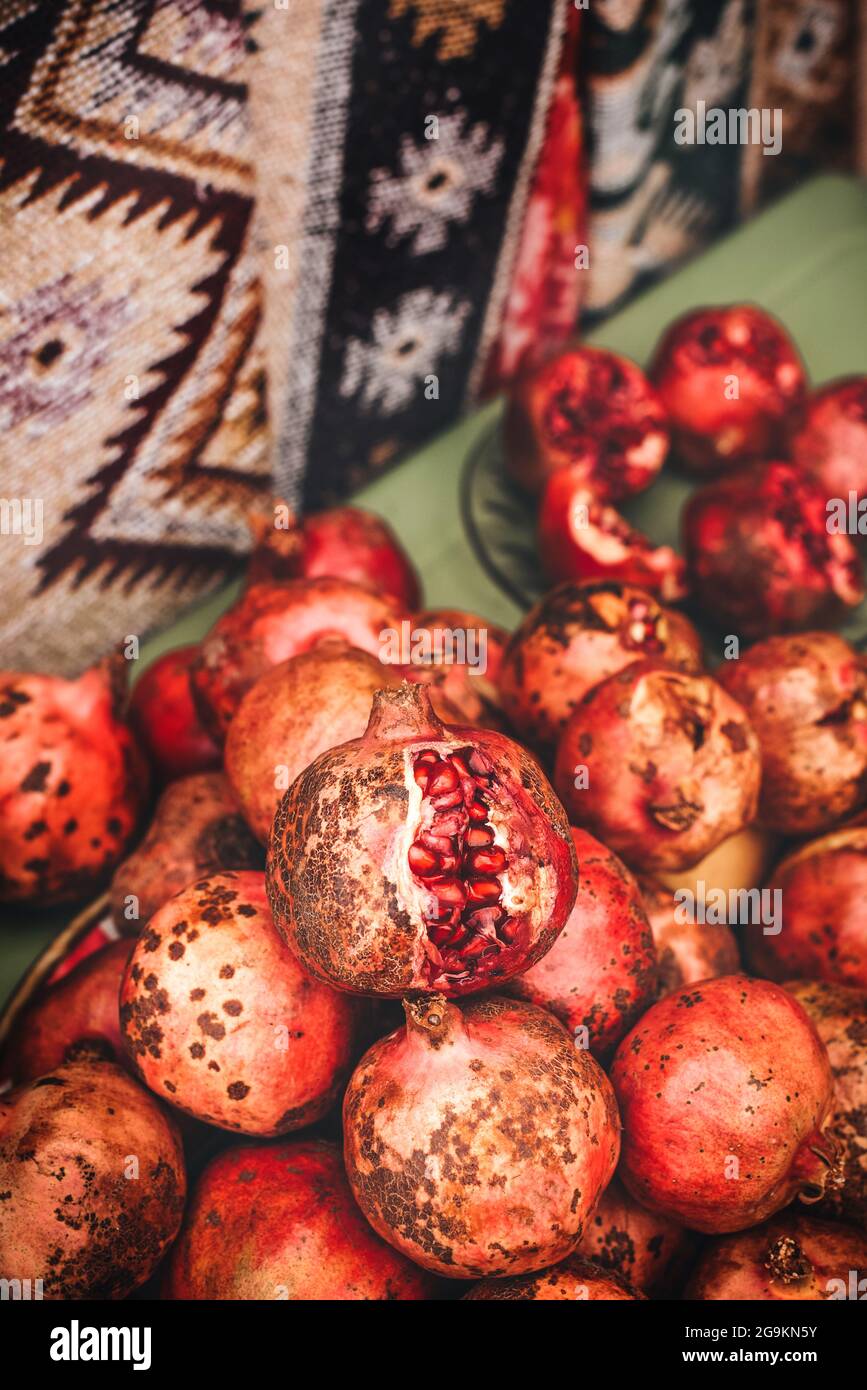 Ripe pomegranate fruits on the market shelf, Overripe burst pomegranate lies on top, close-up. Authentic fruit look. Stock Photo