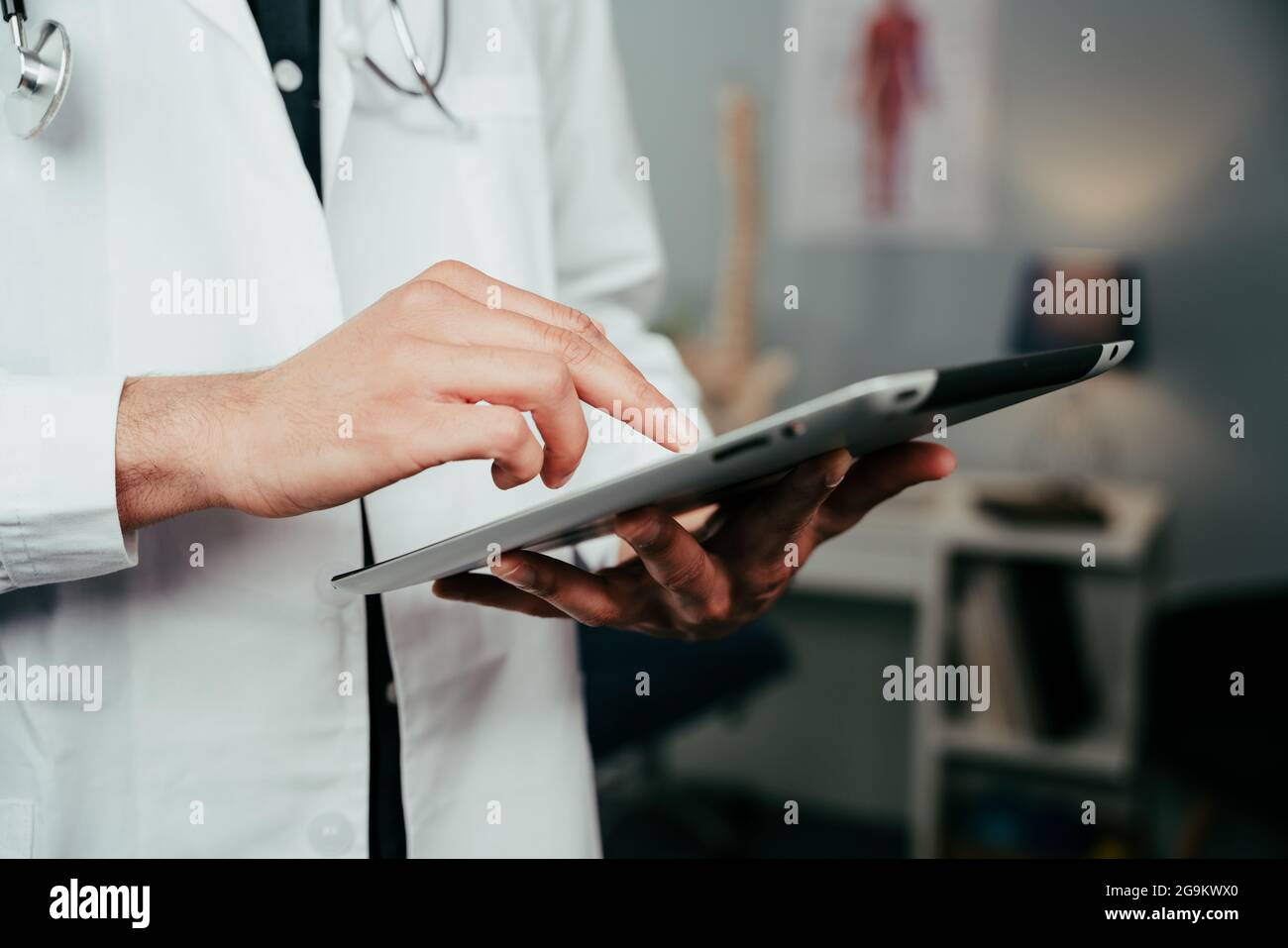Male nurse standing in clinic typing on digital tablet Stock Photo
