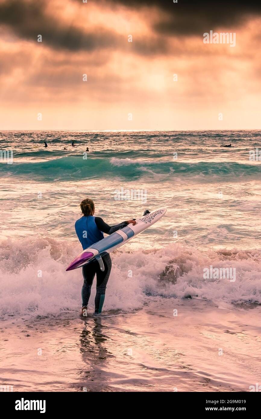 Late evening light over a member of Newquay Surf Lifesaving Club at a training session on Fistral Beach in Newquay in Cornwall. Stock Photo