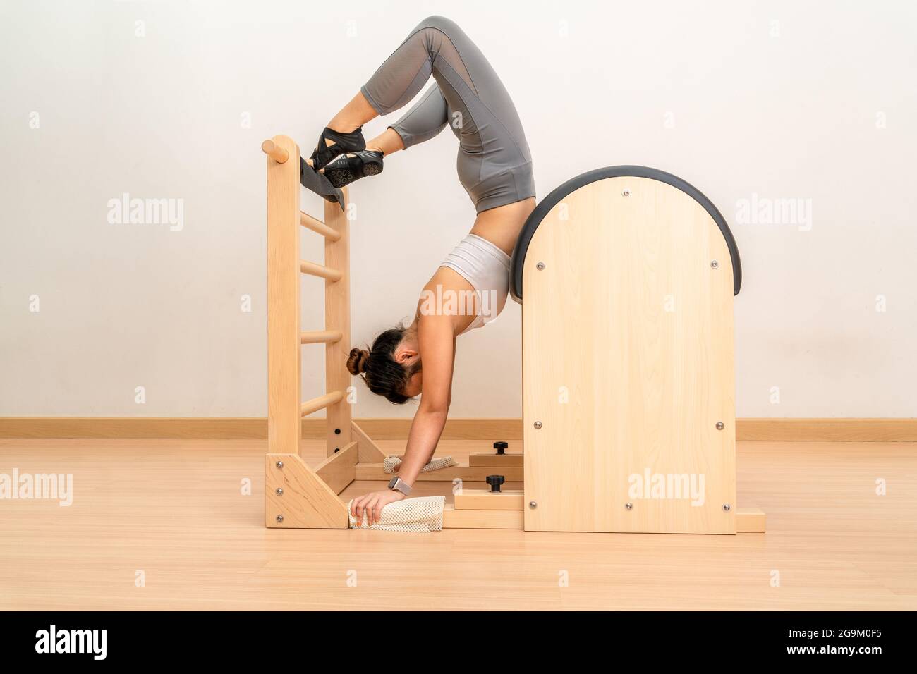 Young Asian Woman Working on Pilates Ladder Barrel Machine during