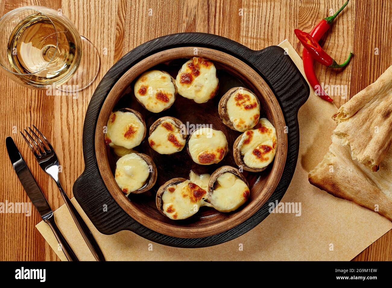 Baked mushrooms caps stuffed with sulguni in wooden bowl Stock Photo