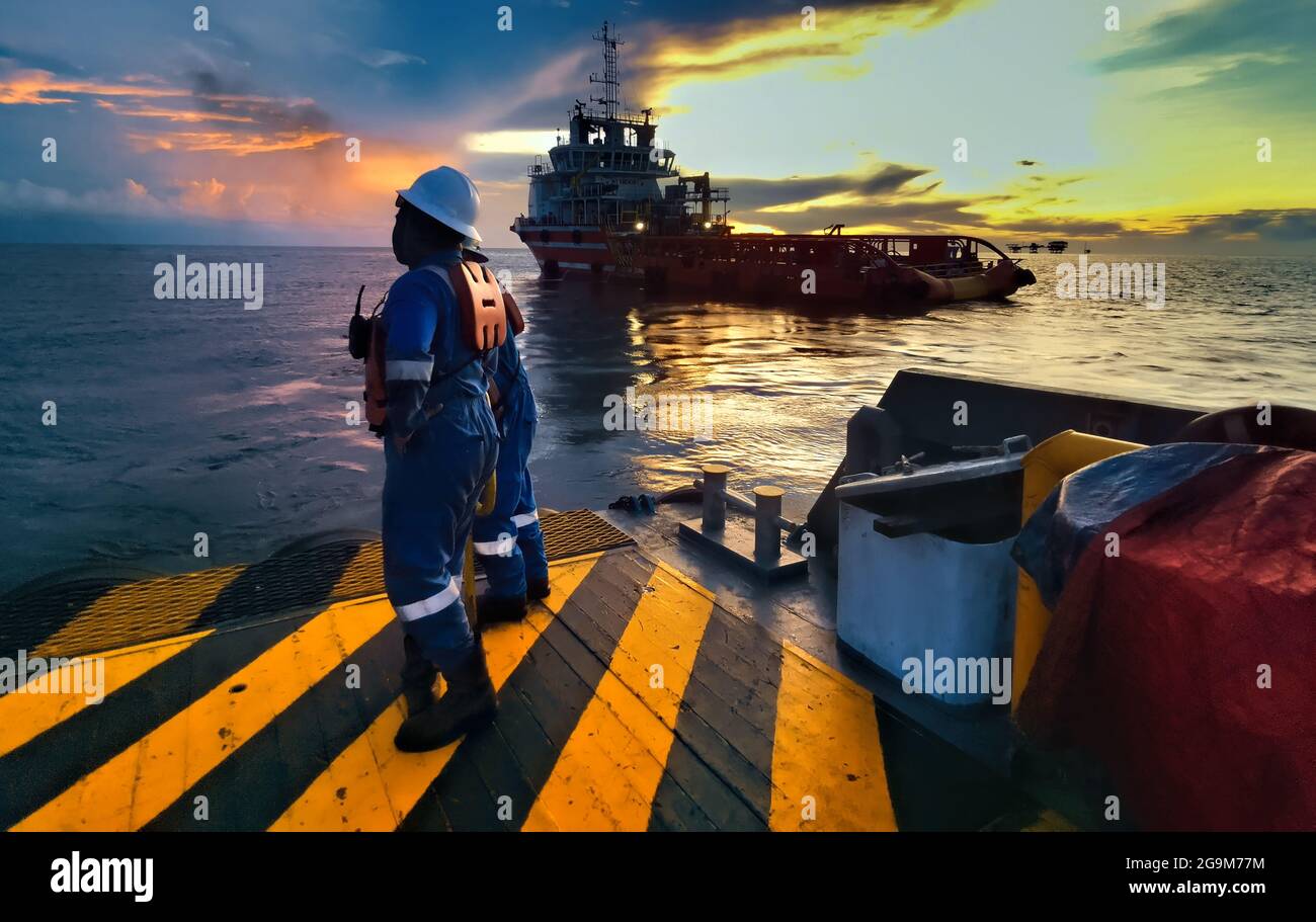 marine crew standing on deck for personal transfer operation during sunset at sea Stock Photo