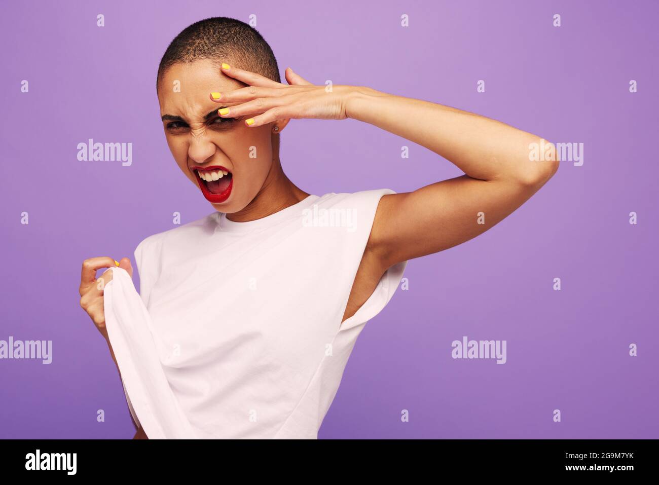 Portrait of a stunning woman with short hair. Female model in while t-shirt looking at camera with cool expression on purple background. Stock Photo