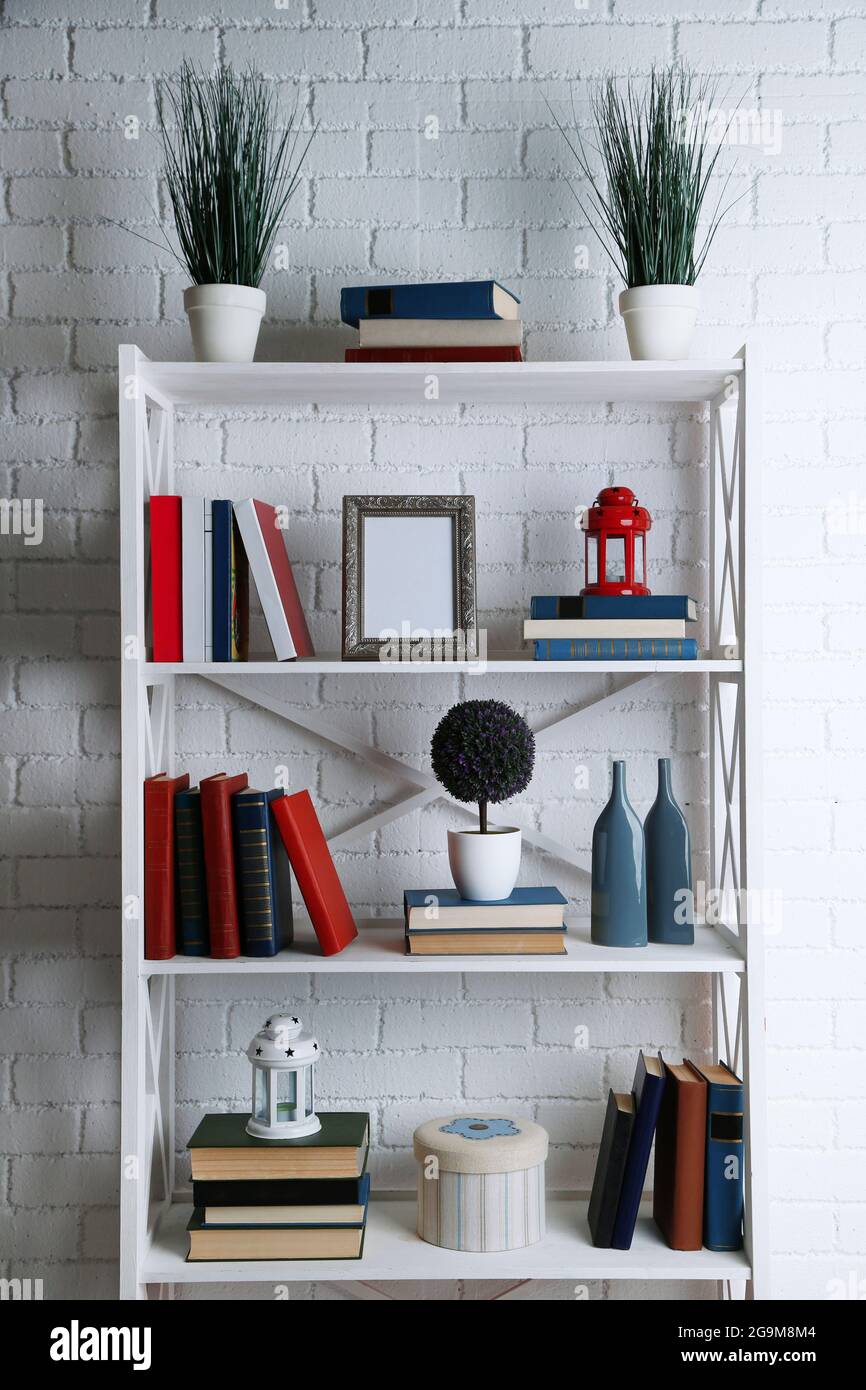 Bookshelves with books and decorative objects on brick wall background ...