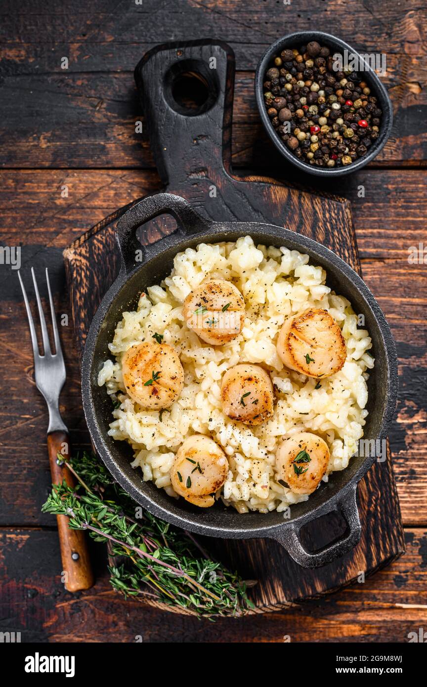 Seafood Risotto with Scallops in a pan. Dark wooden background. Top