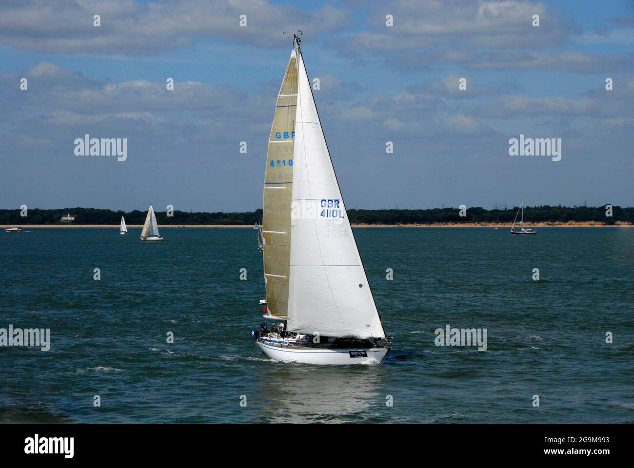 Yacht with gold-coloured mainsail sailing in Southampton Water during Cowes Week regatta, England Stock Photo