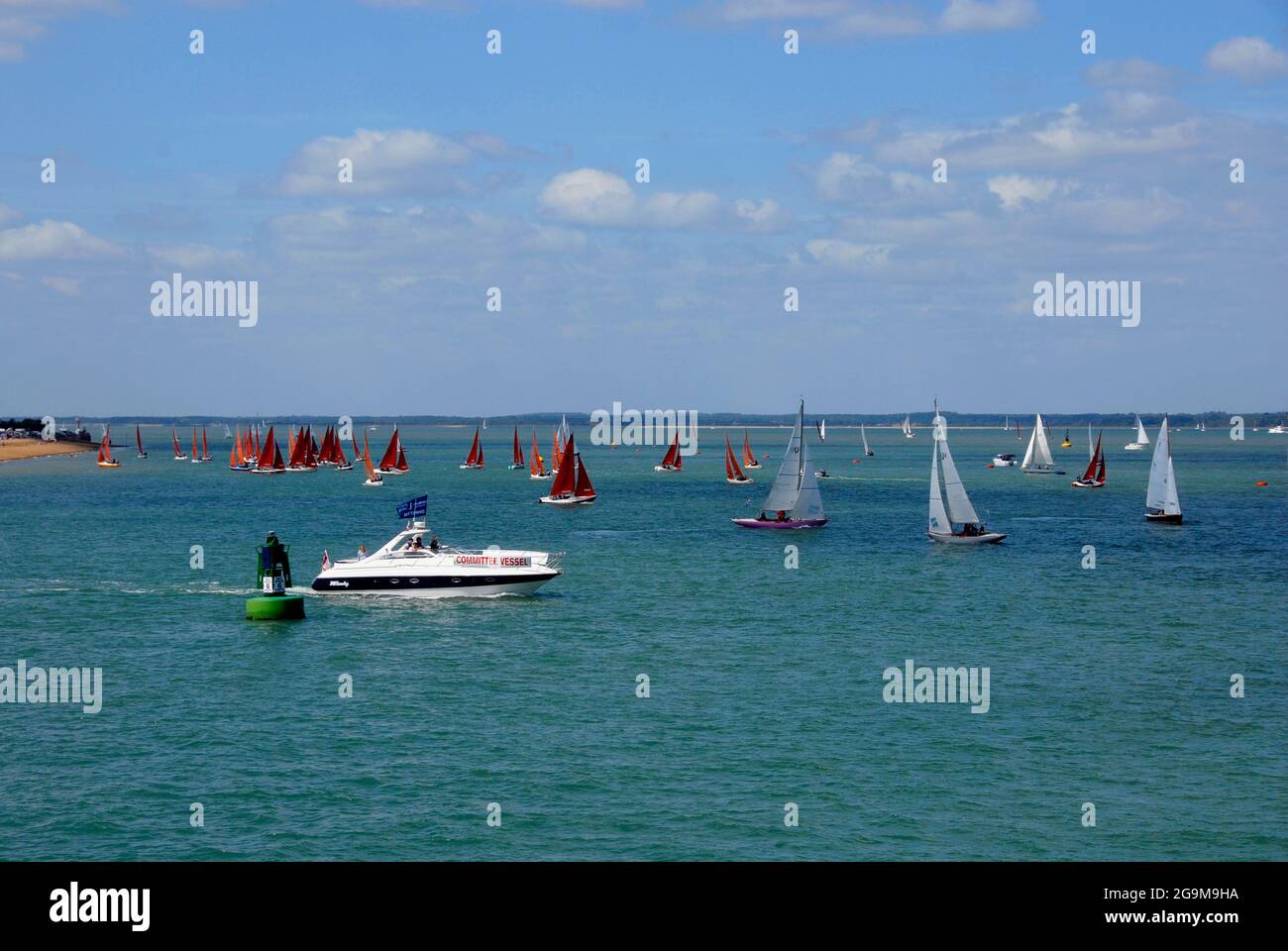 Committee vessel passing by many small yachts in the Solent during Cowes Week regatta Stock Photo