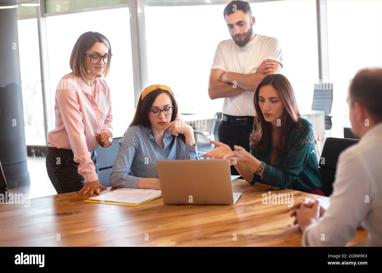 Woman in smart casual clothes sitting on chair and talking with workers during meeting in modern workplace Stock Photo