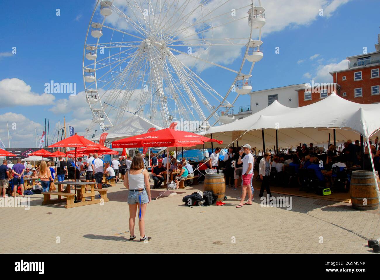 Woman standing watching Ferris wheel during Cowes Week regatta, Isle of Wight, England Stock Photo