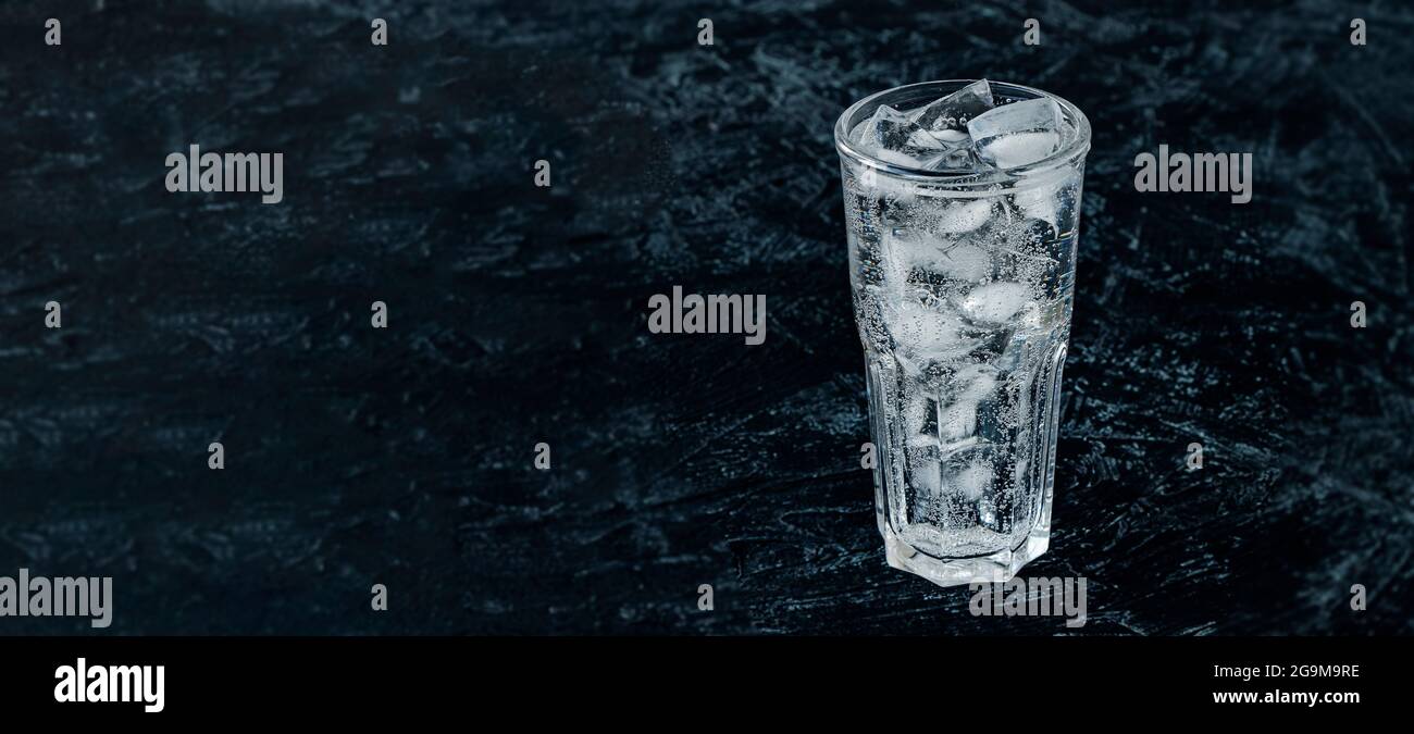 banner with glass with ice water and ice cubes on a black textured ...