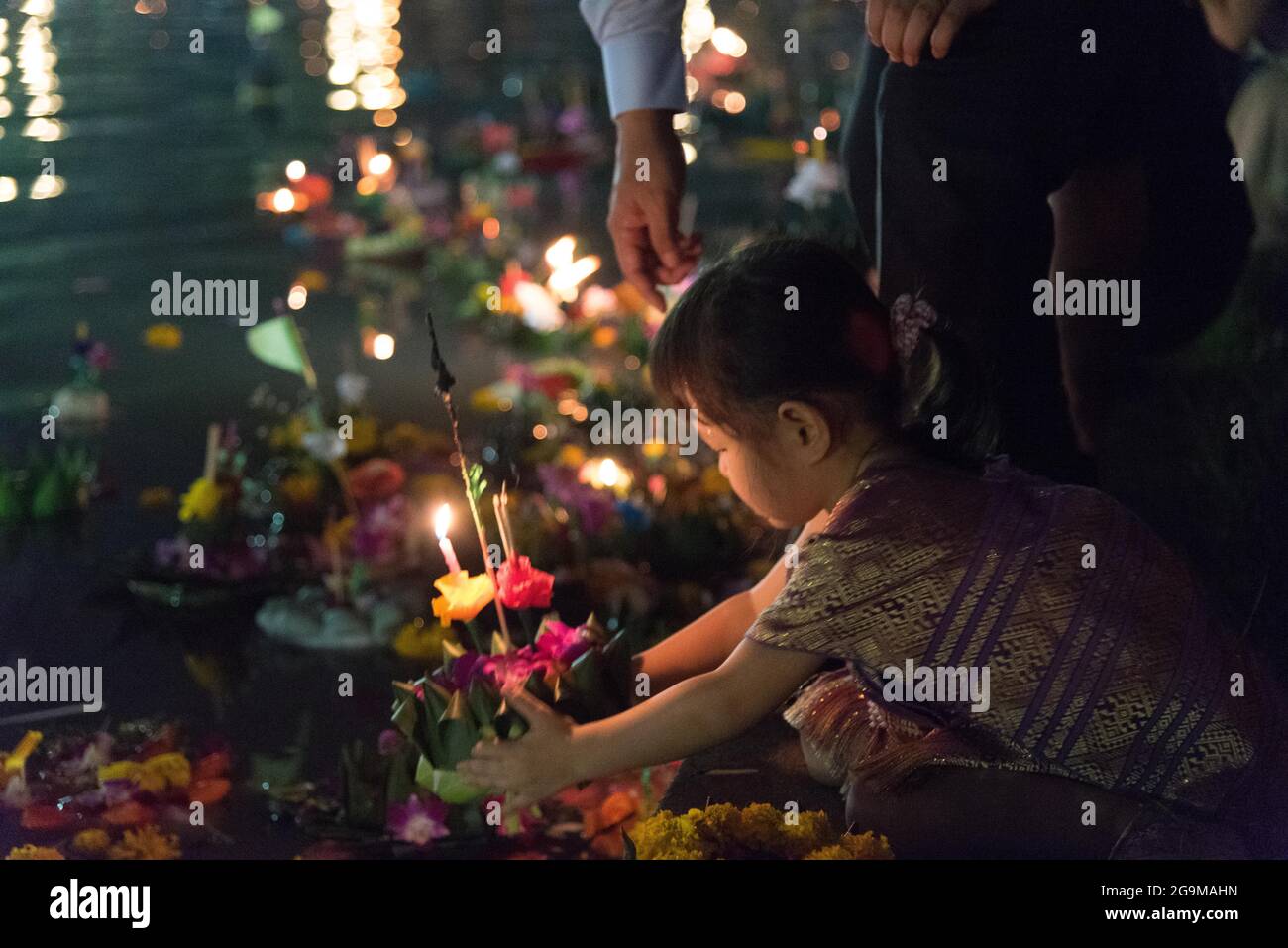 A little Japanese girl in Thai costume launches a krathong on Loy Krathong day in Benjasiri park. Stock Photo