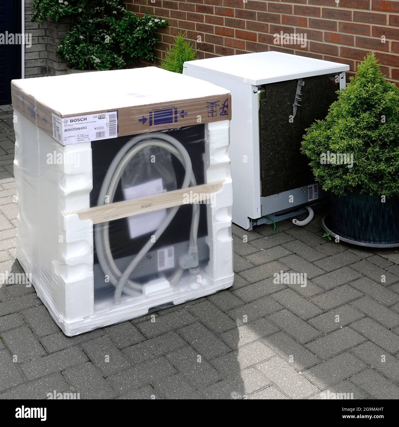 New Bosch white goods domestic dishwasher appliance polystyrene packaging delivered to customers house beside old defective machine for recycling UK Stock Photo