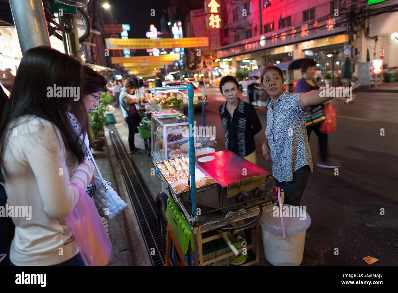A vendor indicates directions to customers in Yaowarat,Bangkok's Chinatown. Stock Photo