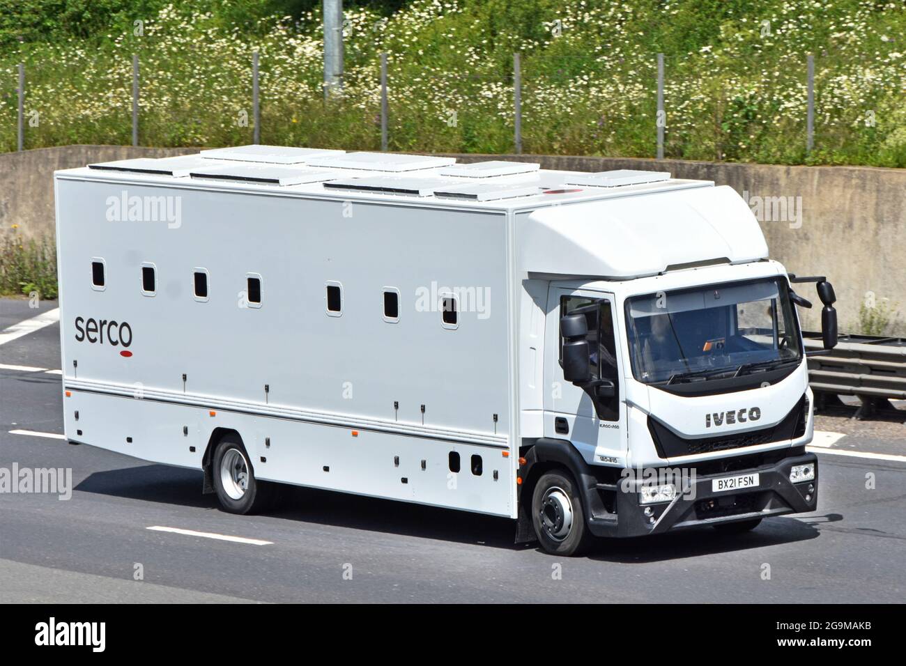 Aerial view front side & roof Iveco prisoner transport van & driver operated by Serco public service transportation business driving along uk motorway Stock Photo
