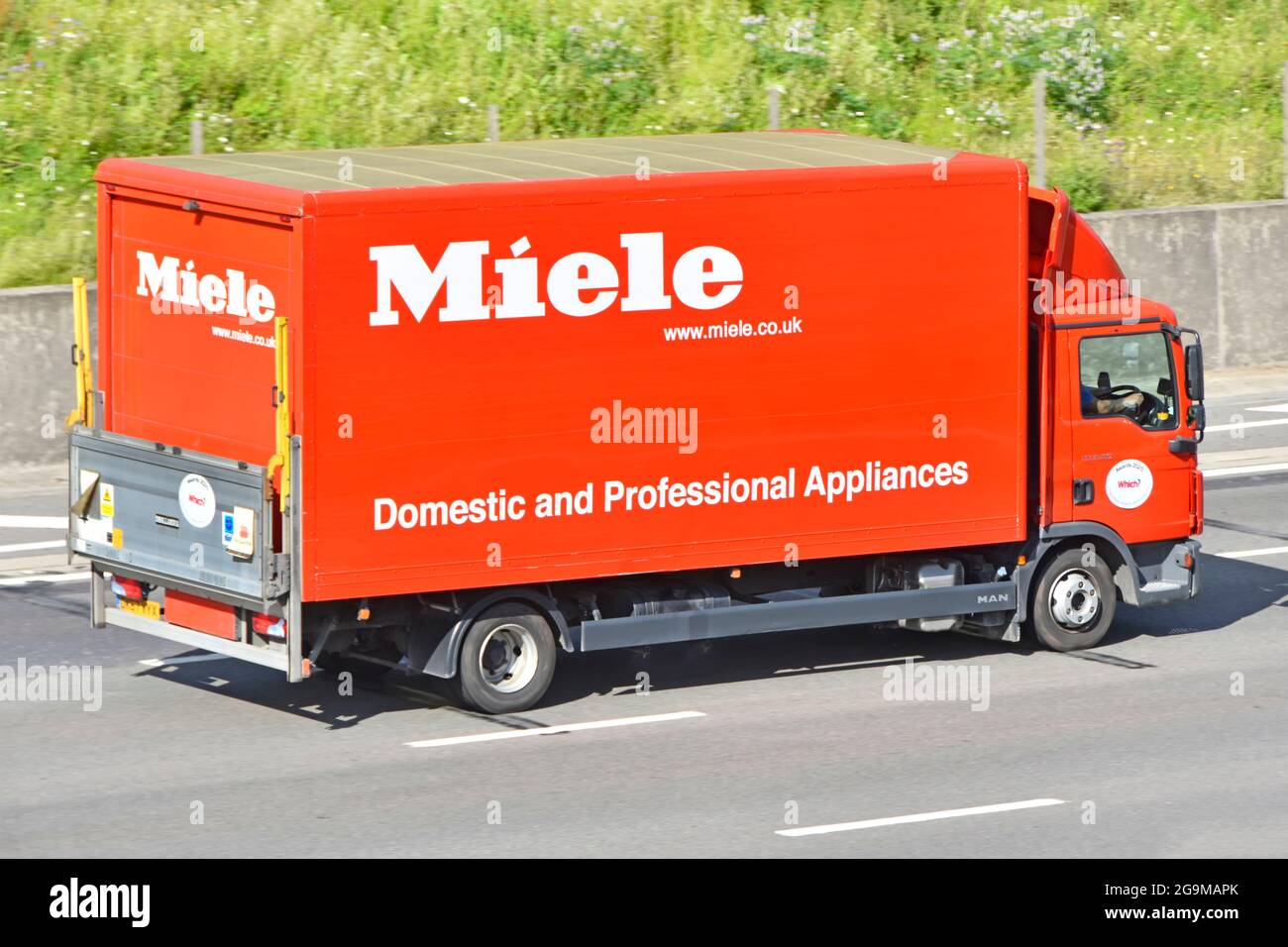 Back tailgate view of Miele business brand advertising for Domestic & Professional electrical appliances on side of lorry truck driving on UK motorway Stock Photo