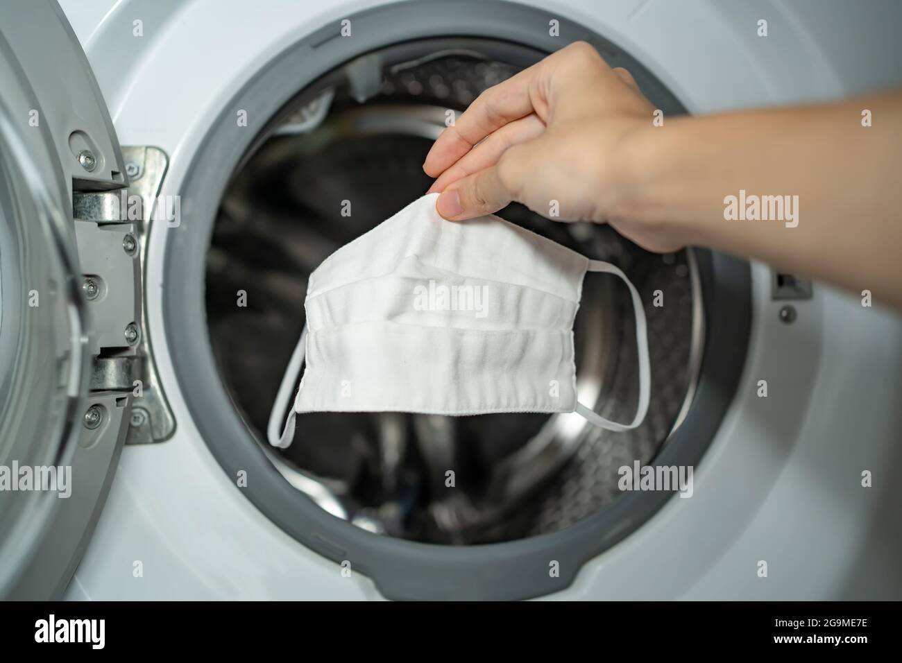 Putting cloth face mask into the washing machine Stock Photo