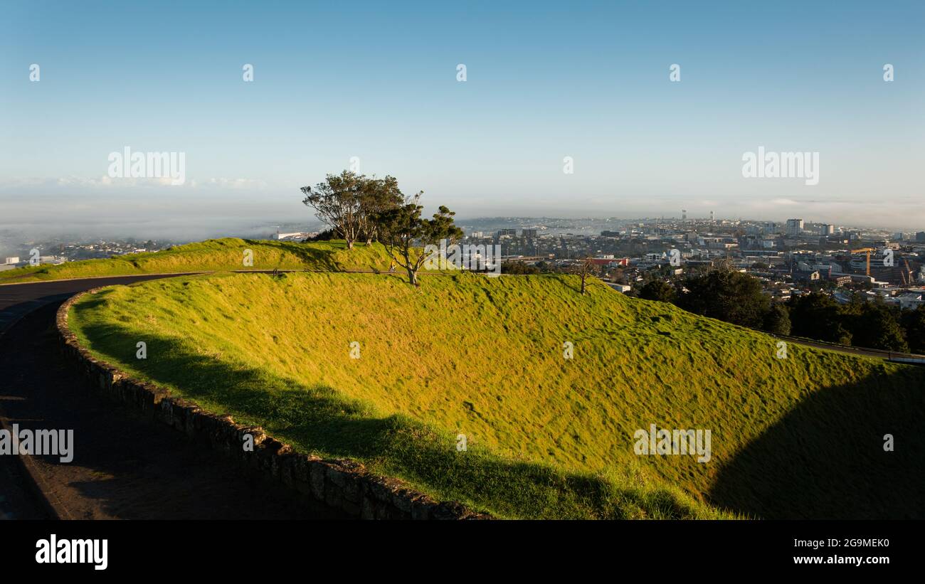 Volcanic crater at the summit of Mt Eden with sweeping view over the Auckland city in the mist, New Zealand Stock Photo