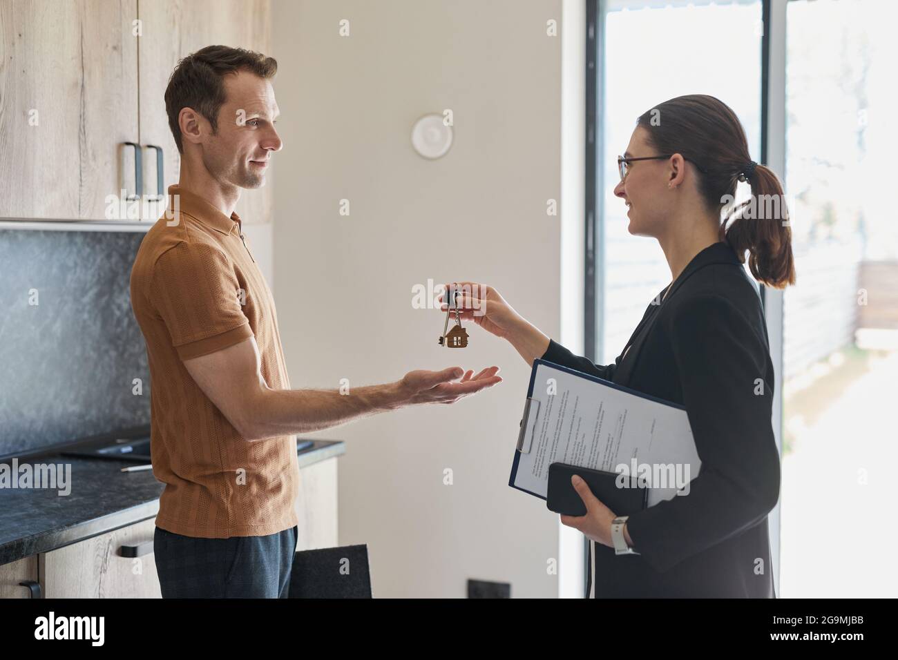 Side view portrait of female real estate agent giving keys to client ...