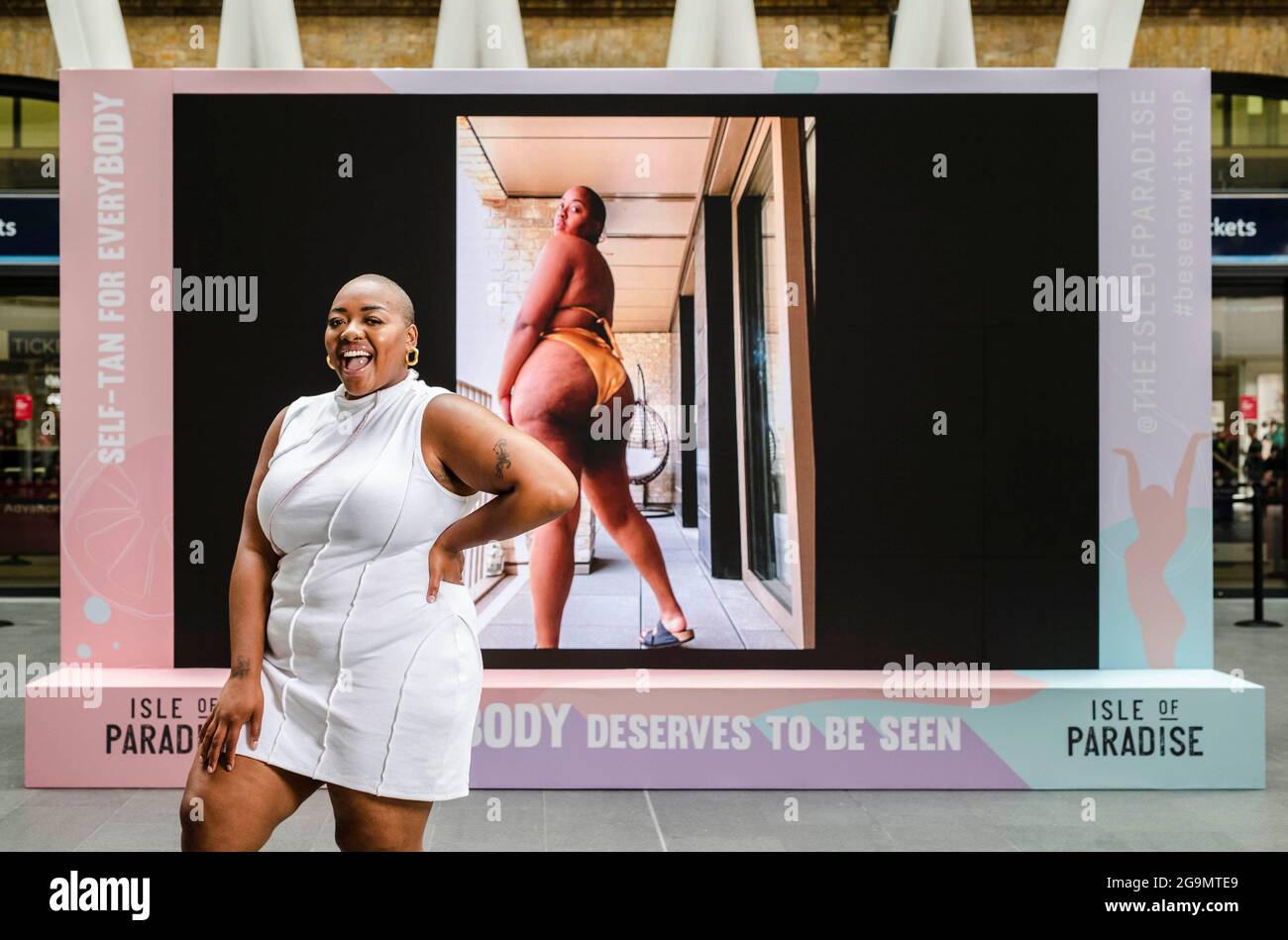 EDITORIAL USE ONLY South London based curvy influencer, Nyome Nicholas-Williams participates in Isle of Paradise's 'al-GLOW-rithm' body confidence campaign, featuring a live billboard at King's Cross Railway Station, to highlight the lack of moderation, selective 'community guidelines' censorship, controlled algorithms and trolling that people face on social media, London. Picture date: Tuesday July 27, 2021. Stock Photo