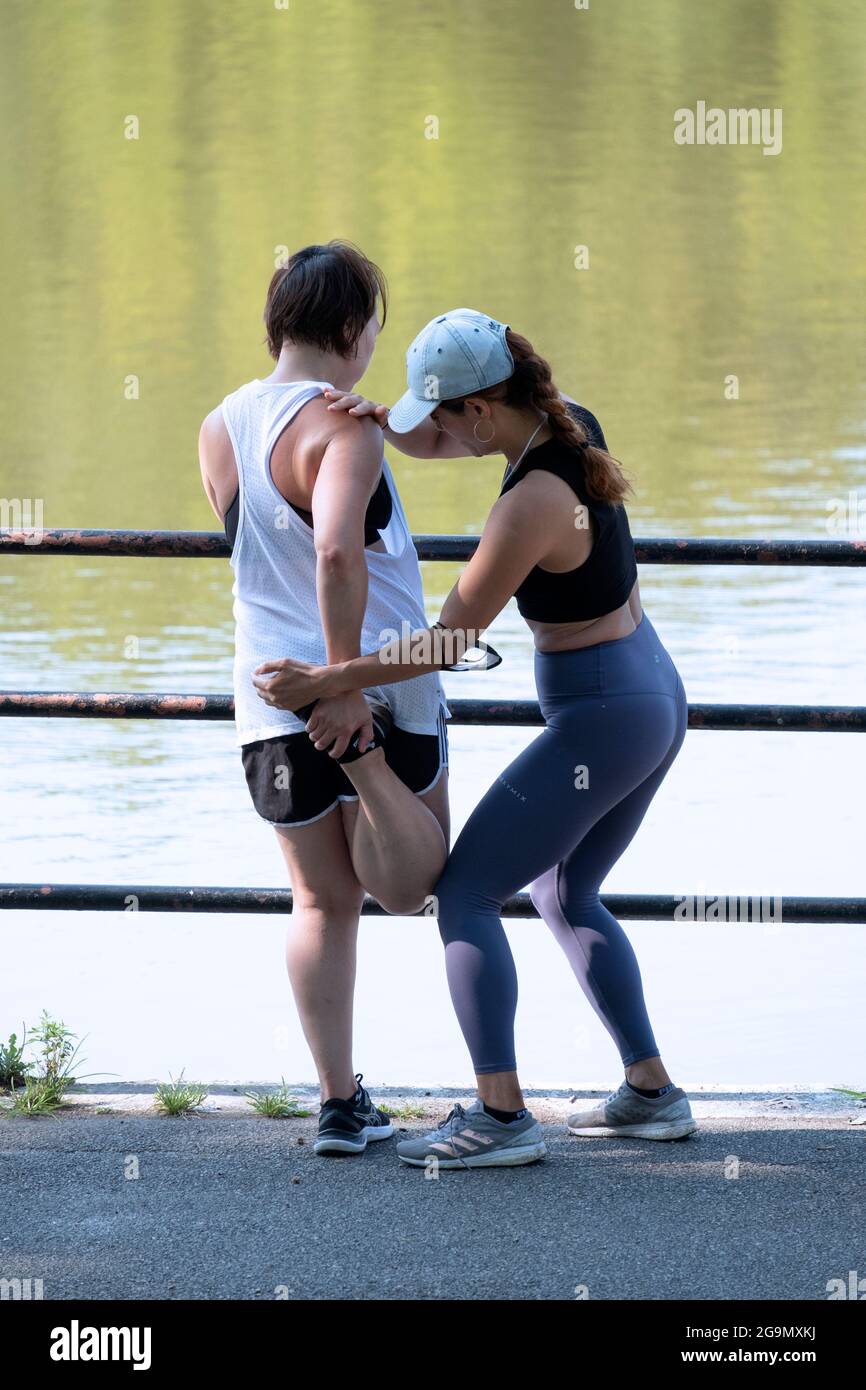 A very fit personal trainer takes a client through hamstring stretching