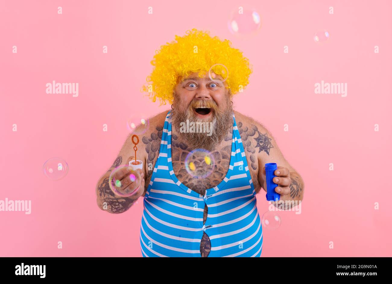 Amazed man with yellow wig in head play with bubbles soap Stock Photo