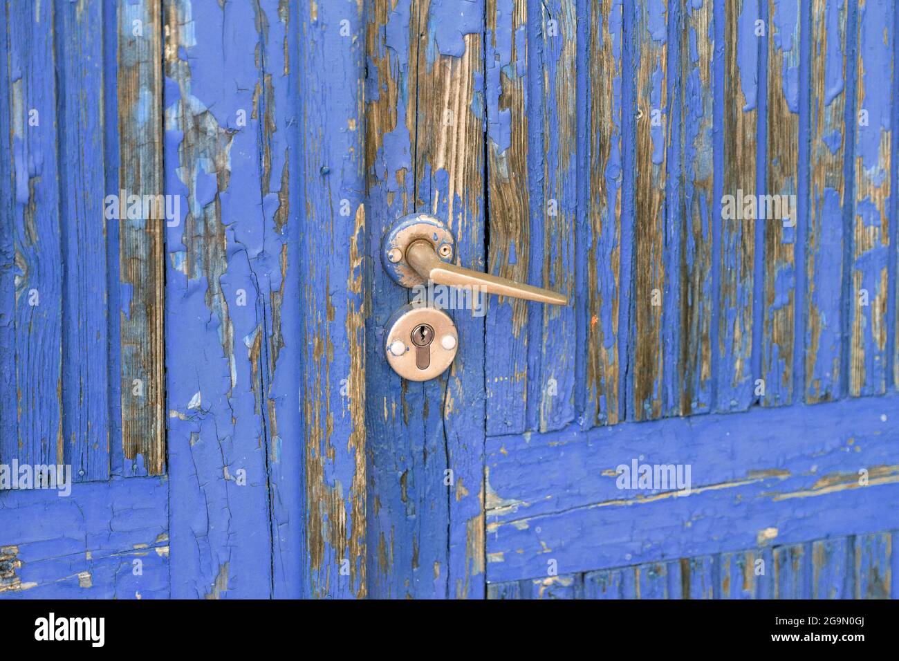Old wooden door with blue paint peeling off Stock Photo
