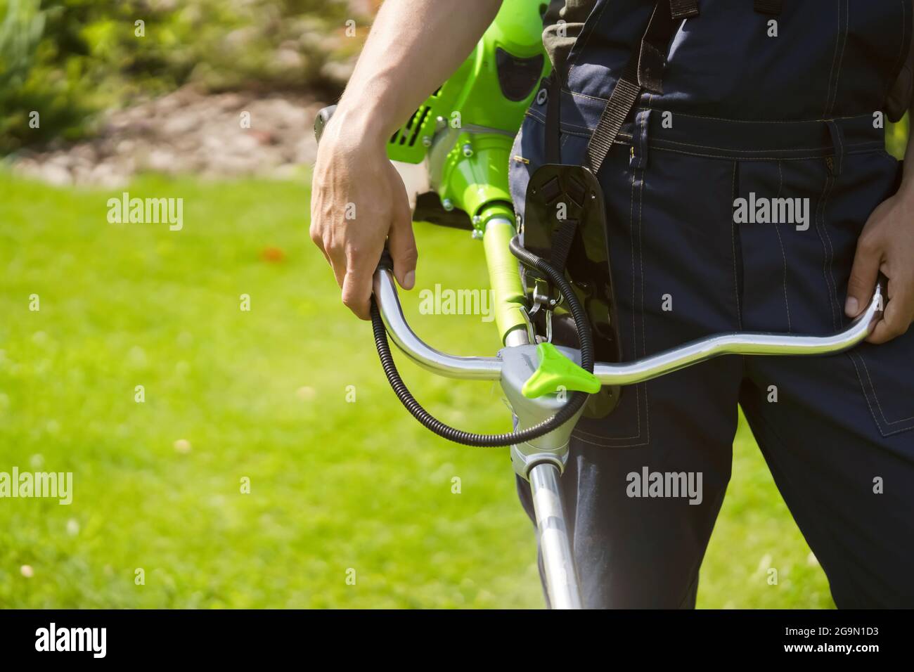 A close up of a white young man moving a lawn with a lawn mower in his hands Stock Photo