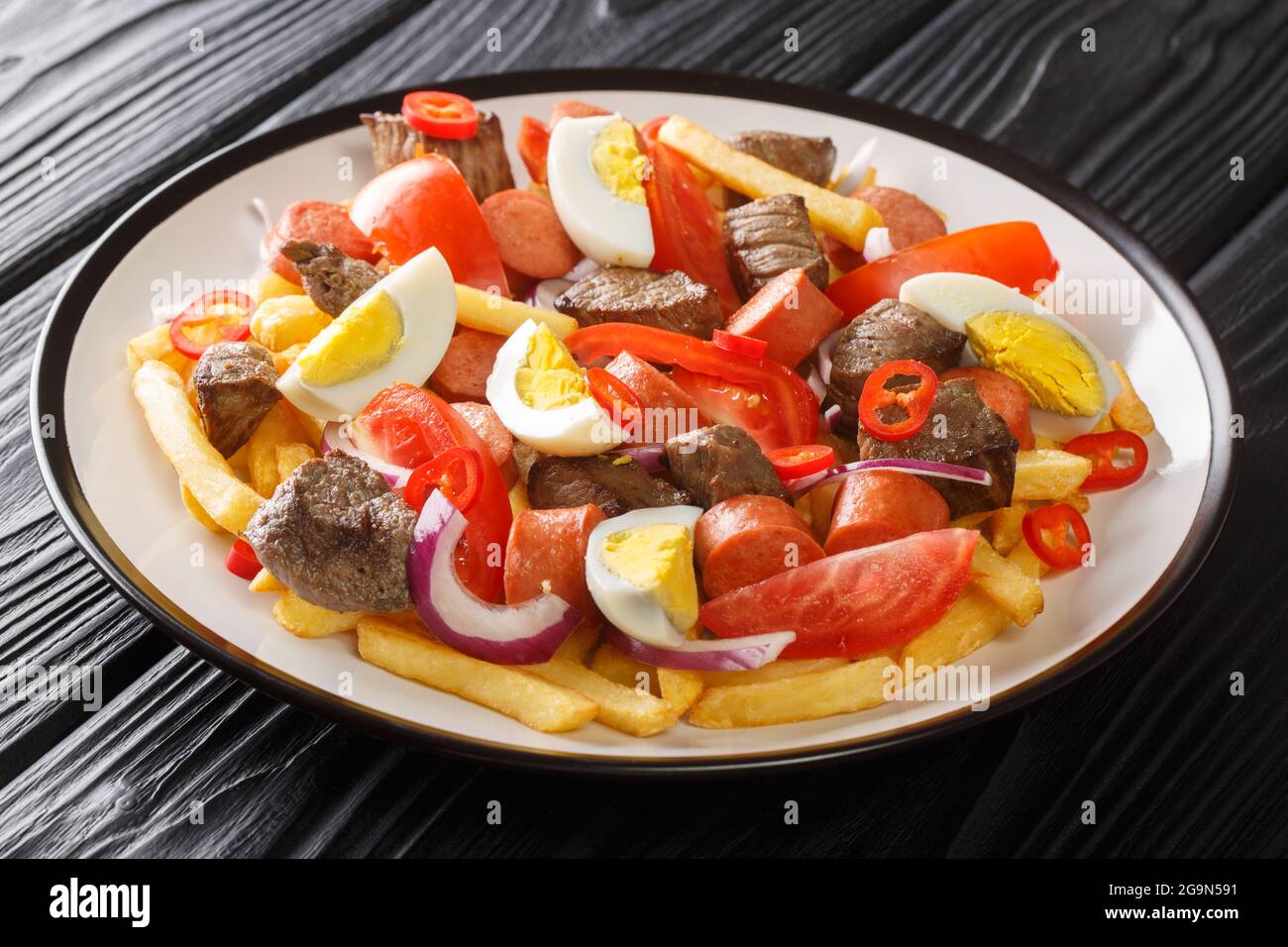 Tasty Pique macho is a type of spicy hearty Bolivian dish that is made by mixing beef, sausage, and vegetables closeup in the plate on the table. Hori Stock Photo